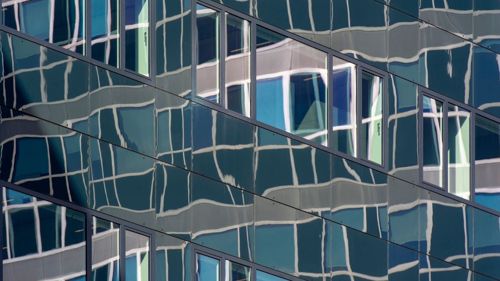 Distorted reflections on a modern glass building facade